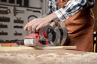 Carpenter sanding wood with belt sander at workshop in wooden board project or woodworking carpentry Stock Photo