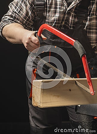 Carpenter sawing a board with a hand wood saw Stock Photo