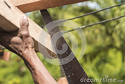 A carpenter saws off the excess edge of a wood rafter. Building or reconstructing a wooden roof frame for a rural home Stock Photo