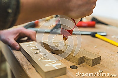 Carpenter squeezing glue onto two pieces of wood with one hand. Woodworking process closeup. Workshop table with tools Stock Photo