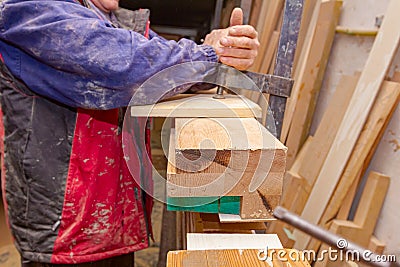 Carpenter is squeezing industrial metal f-clamp after gluing wooden profiles in workshop Stock Photo