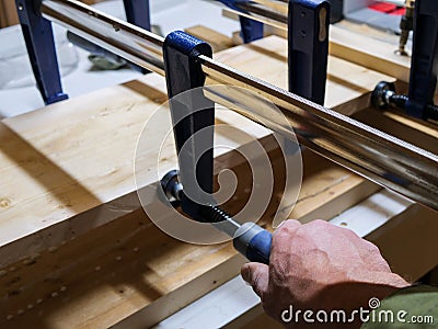 Carpenter squeezing, turning the wood clamp Stock Photo