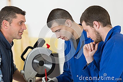 Carpenter teaching apprentices how to use circular saw Stock Photo