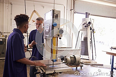 Carpenter Training Male Apprentice To Use Mechanized Saw Stock Photo