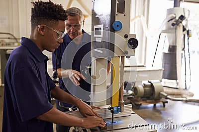 Carpenter Training Male Apprentice To Use Mechanized Saw Stock Photo