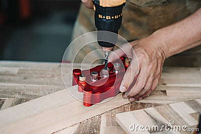 Carpenter use drill bit and centering dowel jig or pocket hole jig tool to make strong joints on wooden plate. woodworking concept Stock Photo