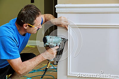 Carpenter using a brad nail gun to complete framing trim Stock Photo