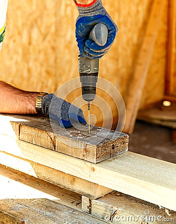 Carpenter using an electric screwdriver screwing wood screw into wood, Install and repair structures fixtures made from wood Stock Photo