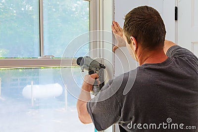 Carpenter using nail gun to moldings on windows, framing trim, Stock Photo