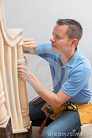 Carpenter Using Sandpaper On Bannister In Home Stock Photo