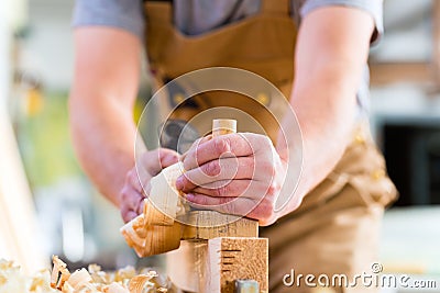 Carpenter with wood planer and workpiece in carpentry Stock Photo