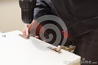 Carpenter at work. Fixing door hinge with electric screwdriver Stock Photo