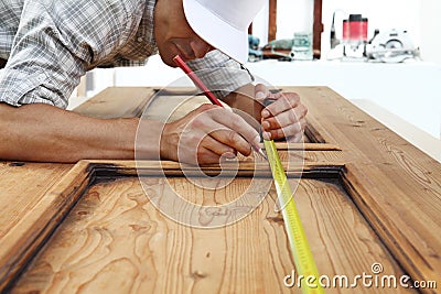 carpenter work the wood, measuring with meter tape a wooden vintage door Stock Photo