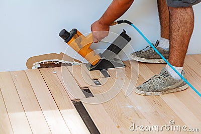 Carpenter worker installing wood parquet board with hammer Stock Photo