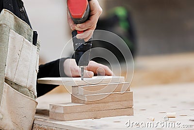 Carpenter working with an electric screwdriver on the work bench. Stock Photo