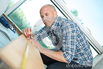 Carpenter working on hand measuring wood board with ruler Stock Photo