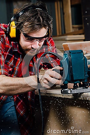 Carpenter working of manual hand milling machine in the carpentry workshop. joiner. Stock Photo