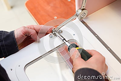 Carpenter working on play furniture. Fixing closers on play kitchen oven door Stock Photo
