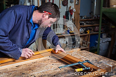 Carpenter working on a Wooden Window Frame in his Workshop Stock Photo