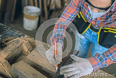 Carpenter is working in a woodworking office.caucasion white Carpenter using tape measure to measure distance and marking with Stock Photo