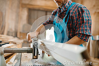 Carpenter works on plane machine, woodworking Stock Photo