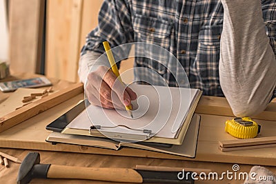 Carpenter writing clipboard notepad project notes and to do list Stock Photo
