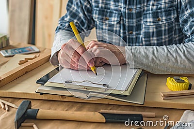 Carpenter writing clipboard notepad project notes and to do list Stock Photo