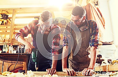 Carpenters with drill drilling plank at workshop Stock Photo