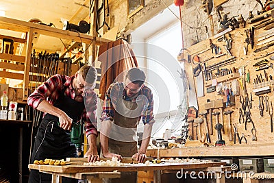 Carpenters with drill drilling plank at workshop Stock Photo