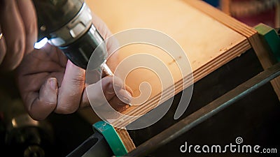 Carpentry industry - man worker drills screws into the piece of plywood Stock Photo