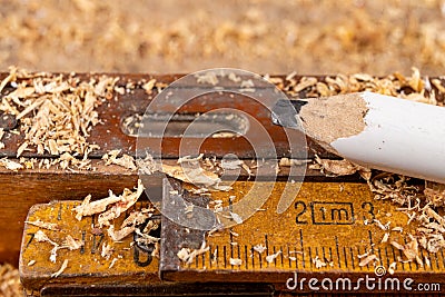 Carpentry measure, spirit level and pencil in sawdust on wooden table. Small carpentry work in a home workshop Stock Photo