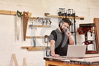 Carpentry small business owner on his phone with a laptop Stock Photo