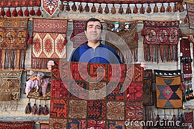 Carpet vendor showing his handmade products in his shop in Bukhara, Uzbekistan Editorial Stock Photo