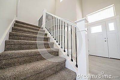 Carpeted staircase with white newel post inside a house with white siding Stock Photo