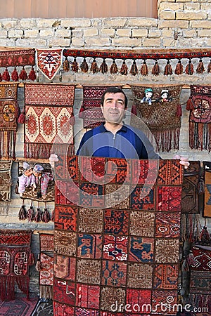 Carpet vendor showing his handmade products in his shop in Bukhara, Uzbekistan Editorial Stock Photo