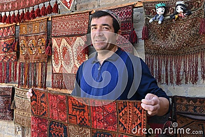 Carpet vendor showing his handmade products in his shop in Bukhara, Uzbekistan Editorial Stock Photo