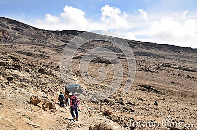carrier on the way to mount kilimanjaro. hard work for the tourists. Luggage on the head Editorial Stock Photo