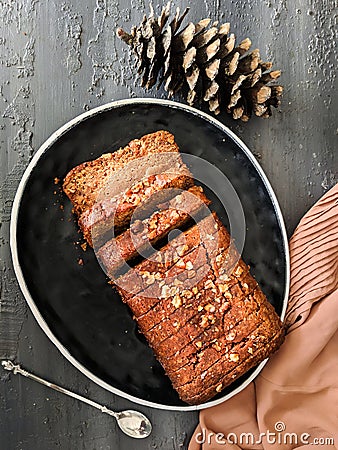 Carrot cake loaf made with oats and almonds, sliced on a black dish, top view. vegan, eggless cake. Healthy, diet, nutrition Stock Photo