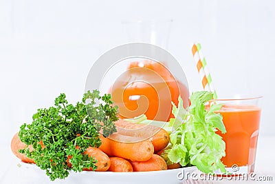 Carrot juice in beautiful glasses, cut orange vegetables and green parsley on white wooden background. Fresh orange drink. Close u Stock Photo