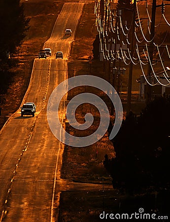 Cars Driving on County Road at Sunset or Sunrise Stock Photo