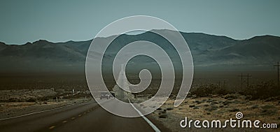 Cars driving down a deserted highway against mountains in the United States Stock Photo