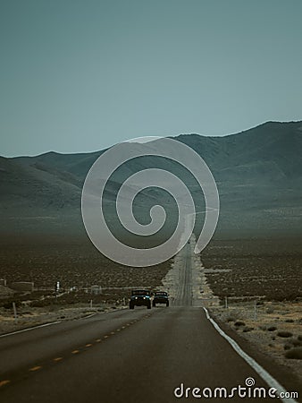 Cars driving down a deserted highway against mountains in the United States Stock Photo