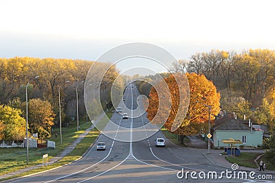 Cars moving on a road, autumnal forest as a background Editorial Stock Photo