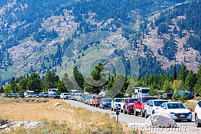 Cars of National Park visitors parked along the road during peak season near Jenny Lake. Editorial Stock Photo