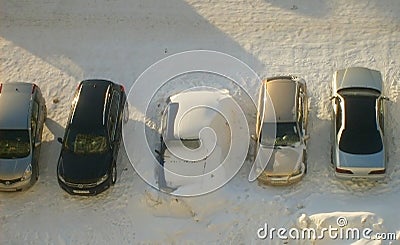 Cars in the parking lot, one car covered with snow heavily. Winter, fight against snow, the concept of public utilities. Editorial Stock Photo