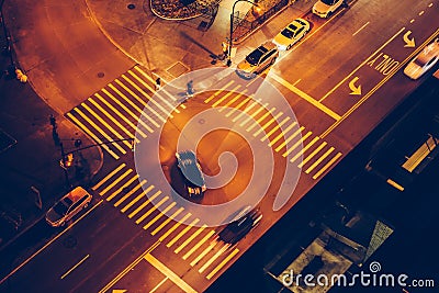 Cars and people on road intersection with signal lights and crosswalks at night time in the city street. Stock Photo