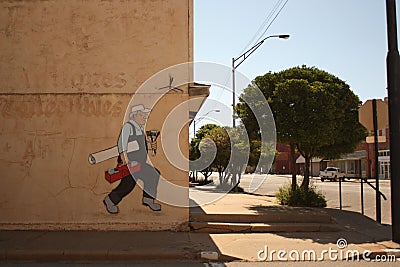 Cartoon mural of a Blue Collar Worker on side of Building in Empty Small Town in Oklahoma Editorial Stock Photo