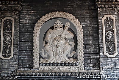 Jambi, Indonesia - October 7, 2018 : Carved statue of Buddhist deity on Vihara Satyakirti walls Editorial Stock Photo