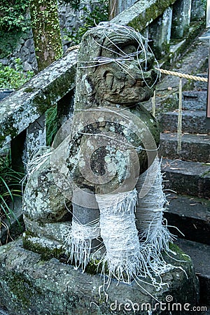 Carved stone dog guardian statue wrapped with white ropes in Nishiyama Shinto Shrine in Nagasaki, Japan. Stock Photo