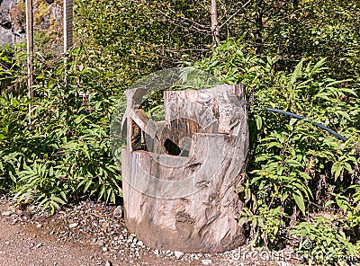 Carved wooden column for drinking mountain water with a Georgian cross on a mountain road in the mountainous part of Georgia Stock Photo